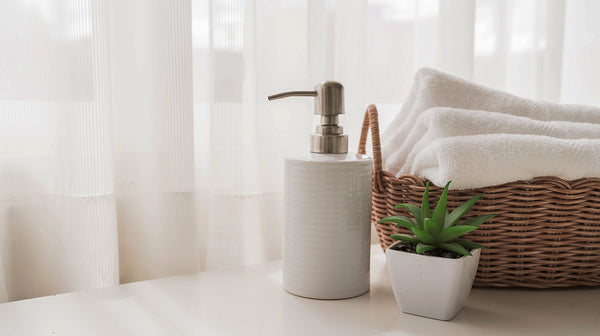 Ceramic soap, shampoo bottles and white cotton towels in basket