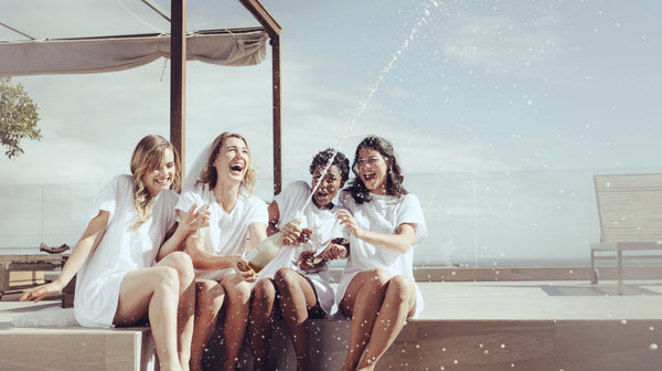 cheerful bride and bridesmaids celebrating hen party with champagne