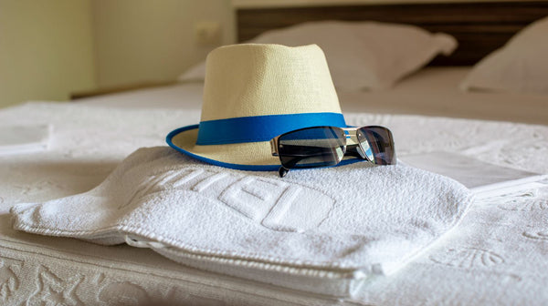 hat towel and sunglasses on bed