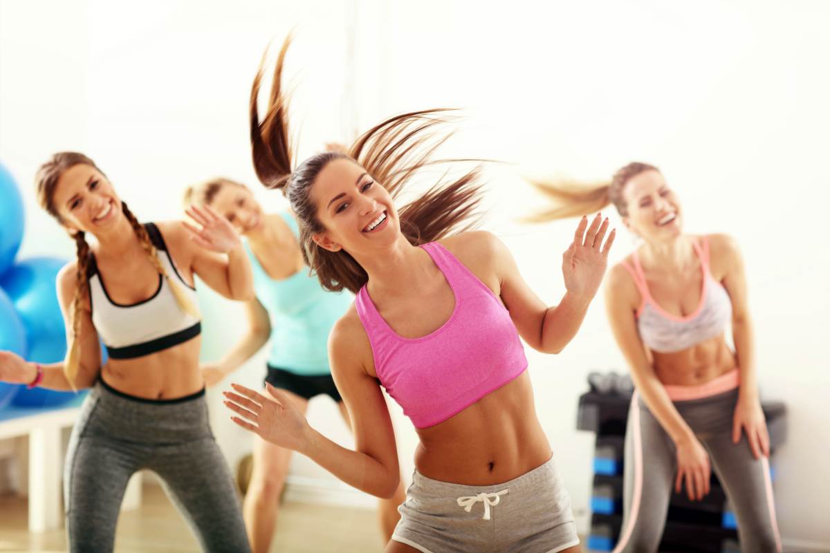 Group of happy people with coach dancing in gym | Bachelorette Party Ideas For A Weekend Of Wellness [INFOGRAPHIC] | relaxing bachelorette party ideas | unconventional bachelorette party ideas