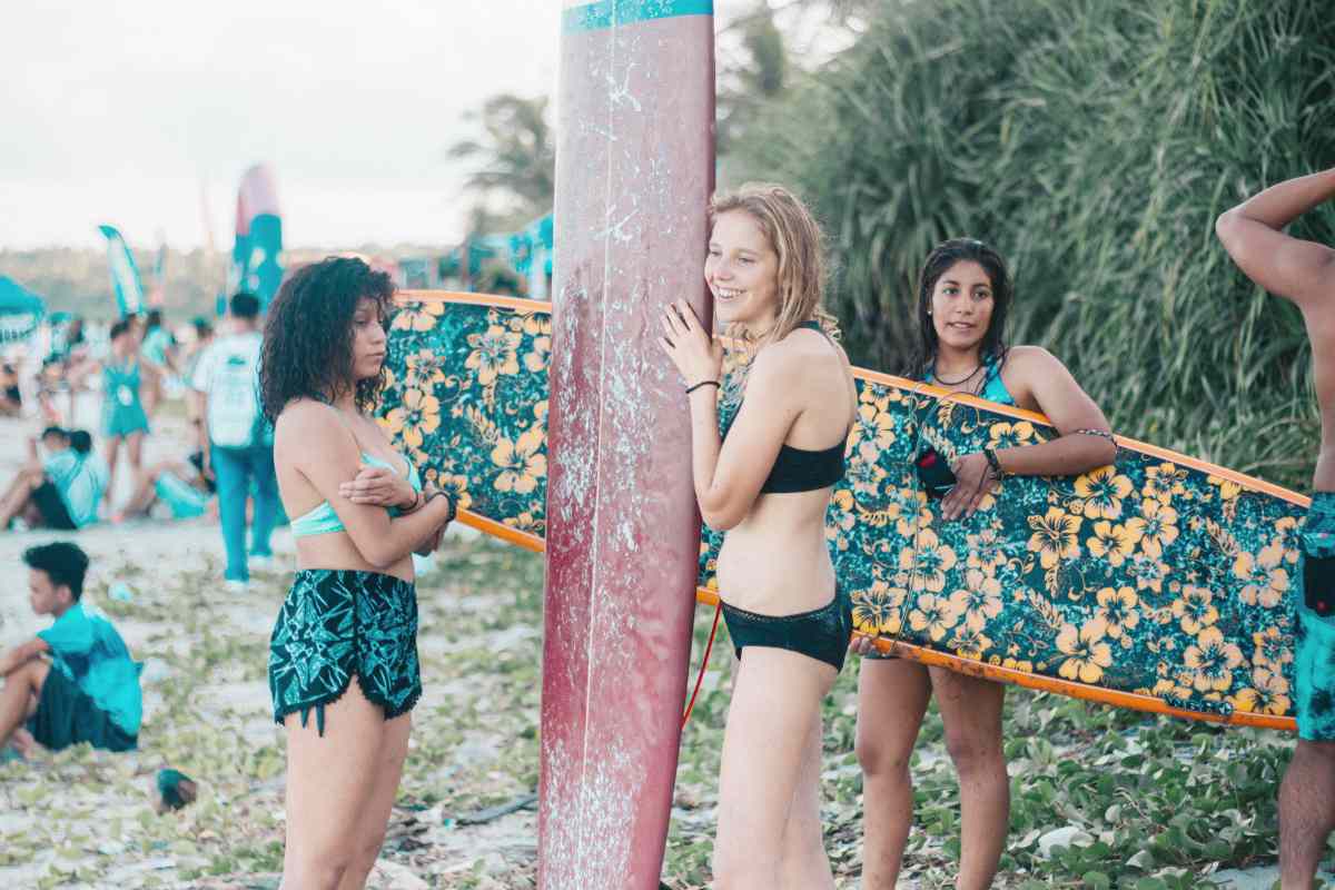 women wearing bikini holding surfboards | Bachelorette Party Ideas For A Weekend Of Wellness [INFOGRAPHIC] | relaxing bachelorette party ideas | r rated bachelorette party games
