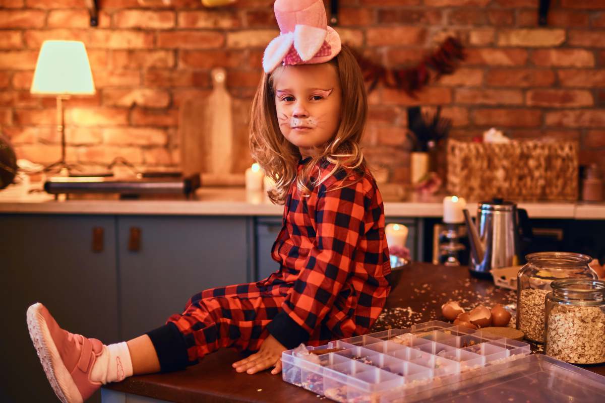Cute little girl in rabbit makeup hat and pajamas sitting on the table | Occasions For Matching Family Pajamas And Why They're The Perfect Gift