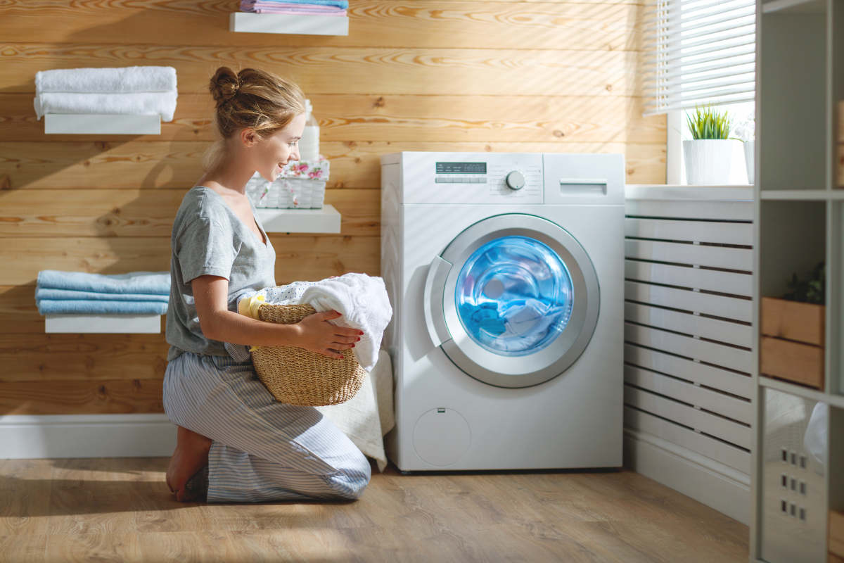 Happy housewife woman in laundry room with washing machine | How To Care For A Velour Fabric Robe | Cleaning Velour Fabric
