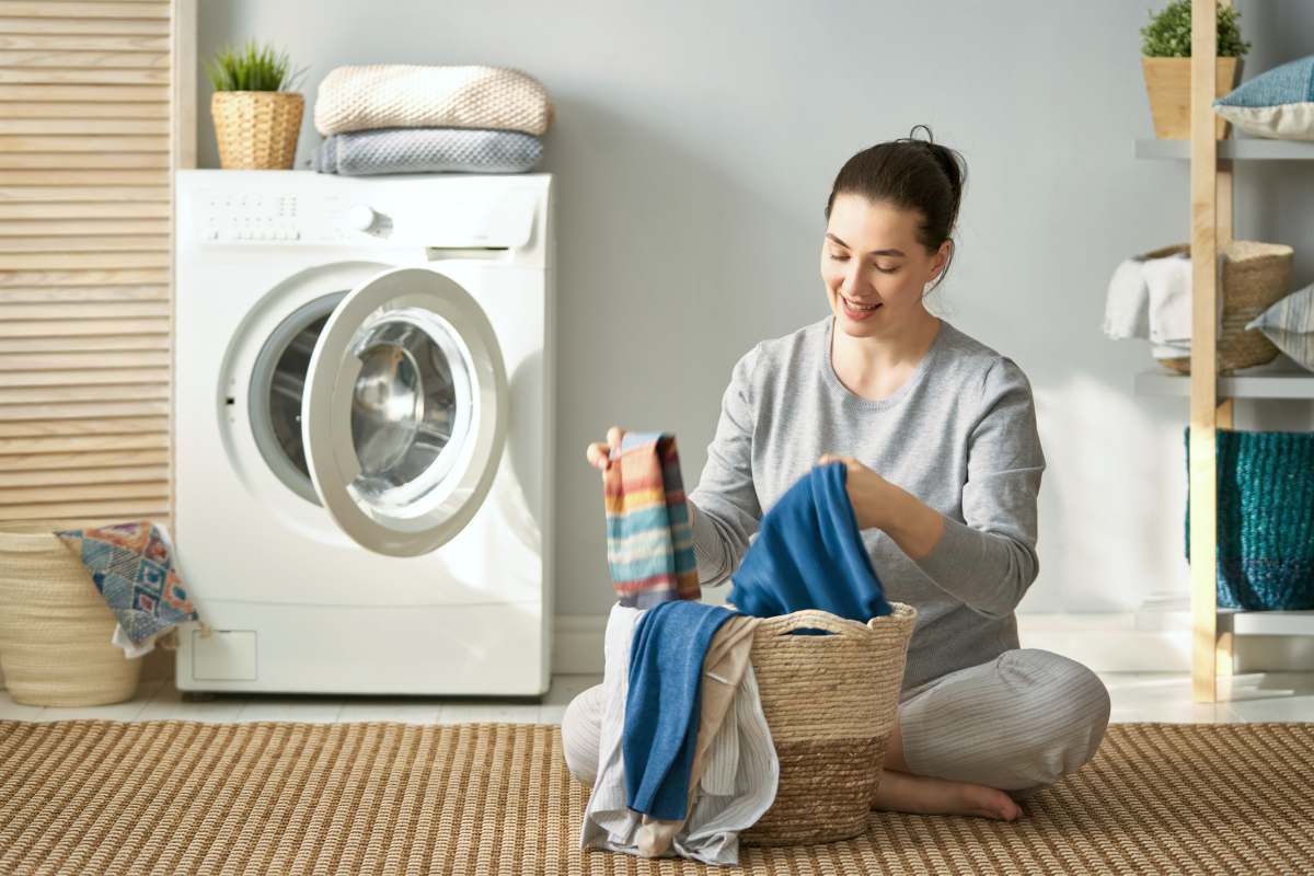 beautiful young woman is smiling while doing laundry at home | What’s The Difference Between Microfleece And Fleece Fabric? | fleece fabric | microfleece fabric