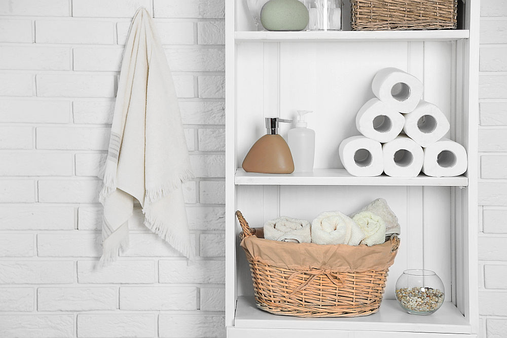 Bathroom set with towels, dispensers, and basket on a shelf in light interior | How To Improve Your Airbnb Essentials And Amenities | airbnb bathroom amenities