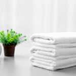 Stack of white clean towels on table in bathroom | Why A White Towel Should Be A Bathroom Staple | white bath towel | Featured