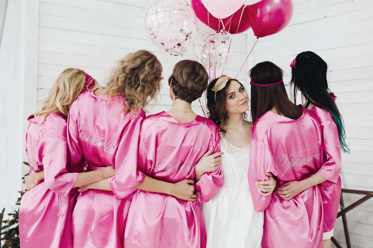 back view of bridesmaids wearing matching satin robes | Bachelorette Party Ideas For A Weekend Of Wellness [INFOGRAPHIC] | relaxing bachelorette party ideas | classy bachelorette party ideas