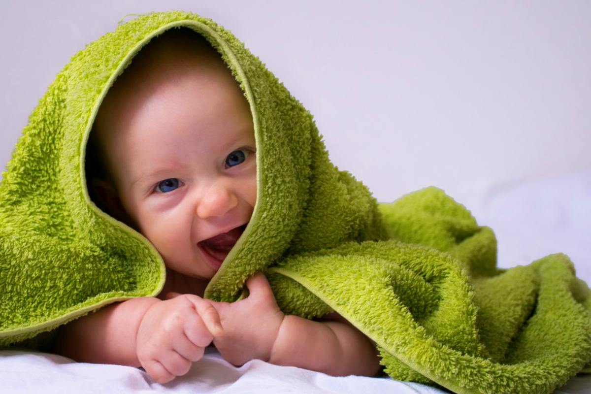 Happy, smiled half-year baby girl in a towel after bathing | Use This Guide Next Time You Buy Bath Towels | bath towels | best bath towels