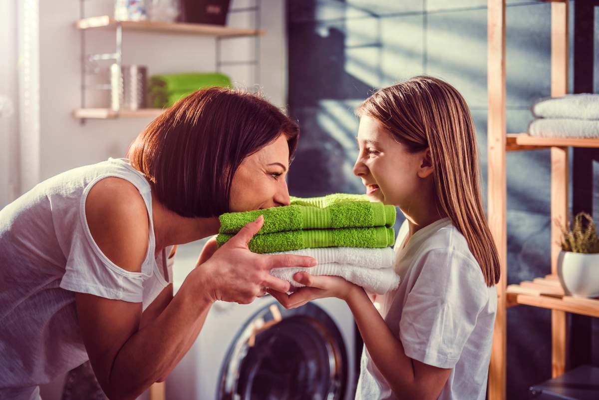 Mother and daughter smelling fresh green towels at laundry room | Use This Guide Next Time You Buy Bath Towels | bath towels | best bath towels