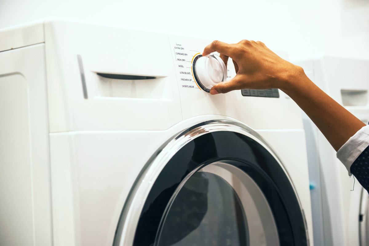Person adjusting control on front load clothes washer | Tips Before Washing A Terry Cloth Robe