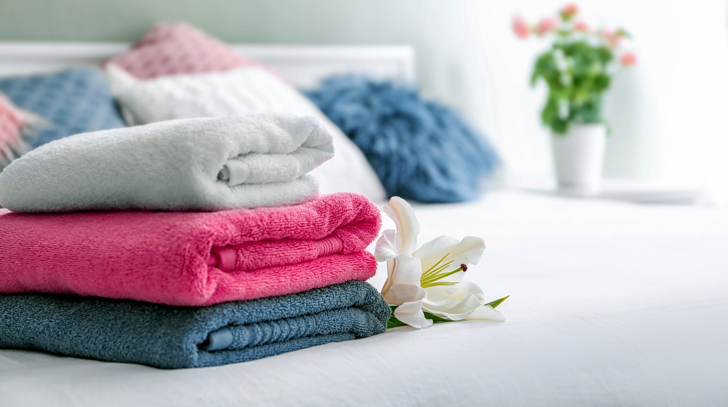 Featured | Stack of clean towels on bed | How To Fold Towels | Step by Step Guide