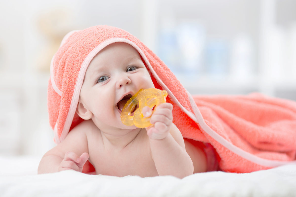 Cute baby with teether under a hooded towel after bath | Reasons To Choose Turkish Cotton