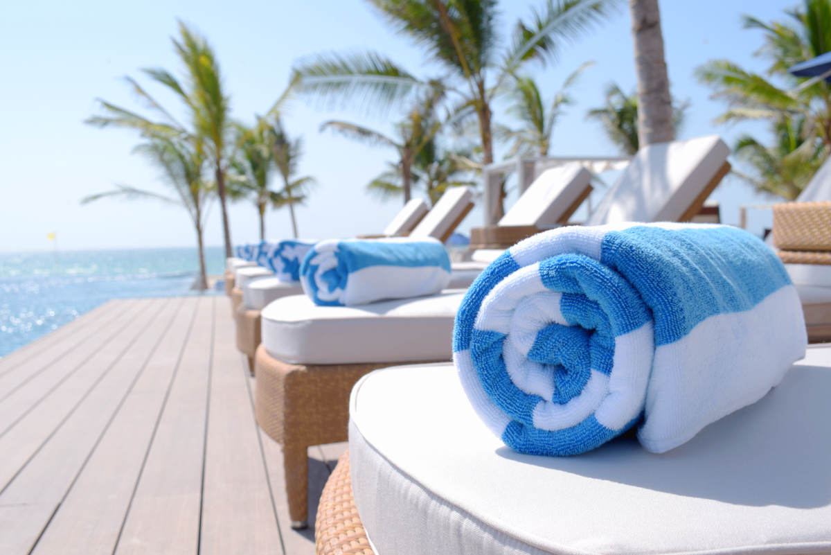 Rolled up towels on sunbeds by pool | Tips To Find A Beach Towel That Will Last
