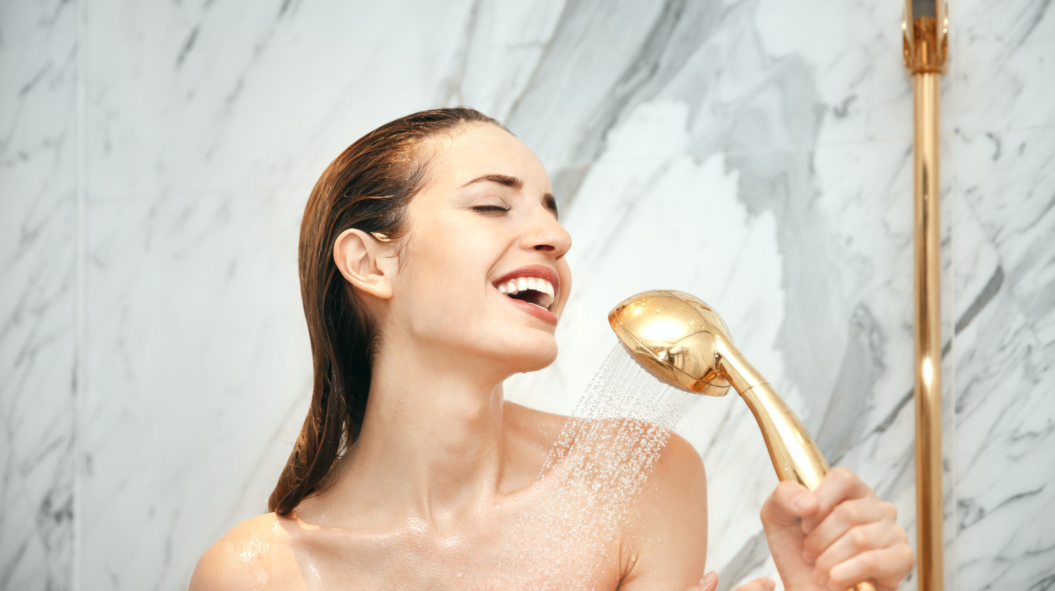 Feature | Young beautiful woman taking shower in bathroom | Bath Accessories You Need For Everyday Self-Care