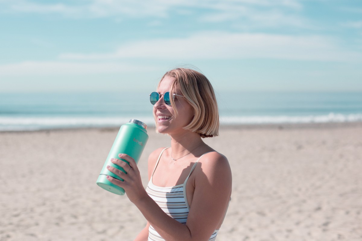 woman holding tumbler | Beach Essentials You Shouldn’t Be Without On Your Next Trip | beach essentials list