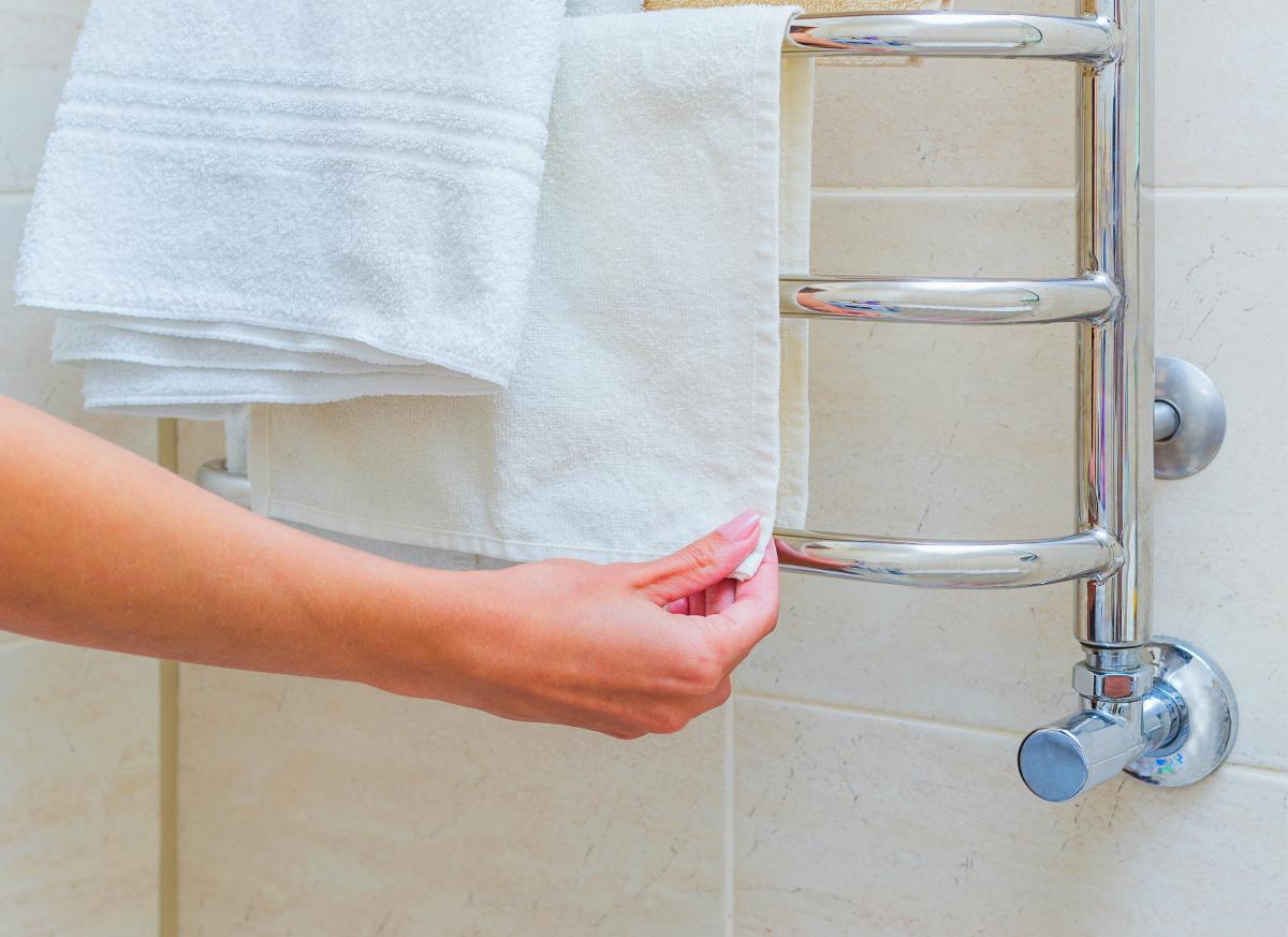 person placing towel on towel warmer | Towel Warmer: The Bath Accessory You Didn’t Know You Needed | towel warmer | towel warmer rack