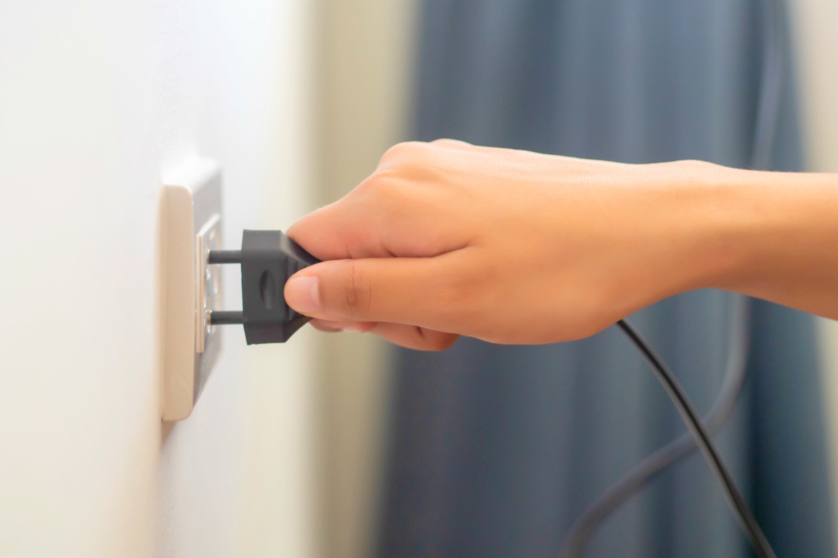person plugging electrical wire into the wall socket | Top Things Every Motel Room Should Have | motel room | items for motel rooms