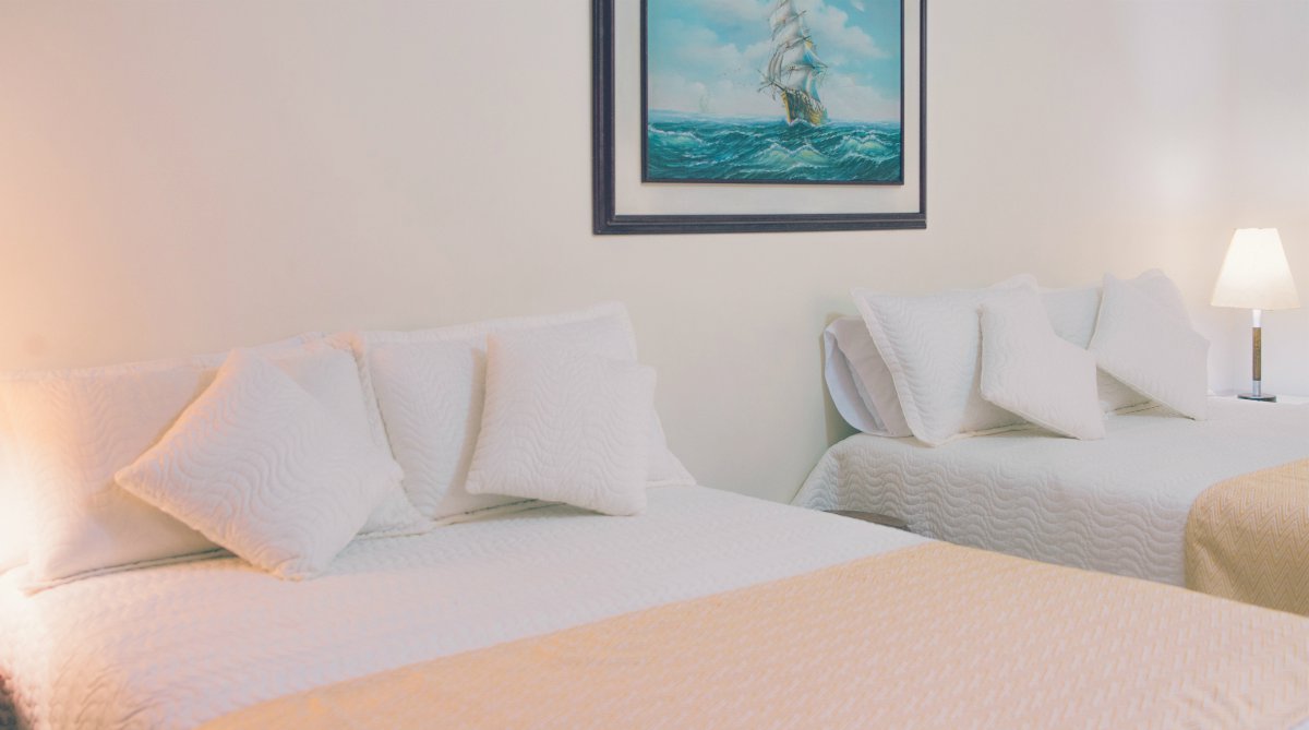 two white bed near wall | Top Things Every Motel Room Should Have | motel room | items for motel