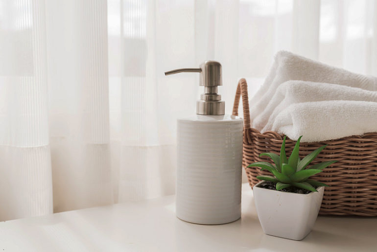 Ceramic soap, shampoo bottles and white cotton towels in basket | Airbnb Towels: Everything You Need To Know | bnb towels | Featured