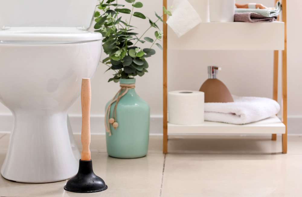 Plunger near toilet bowl in bathroom | Airbnb Bathroom Essentials To Stock For Your Guests | airbnb bathroom