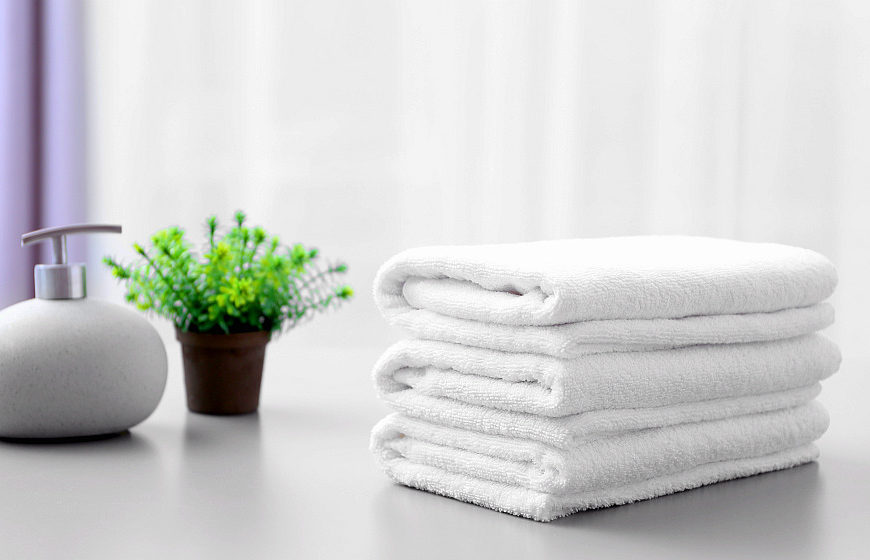 Stack of white clean towels on table in bathroom | Why A White Towel Should Be A Bathroom Staple | white bath towel | Featured