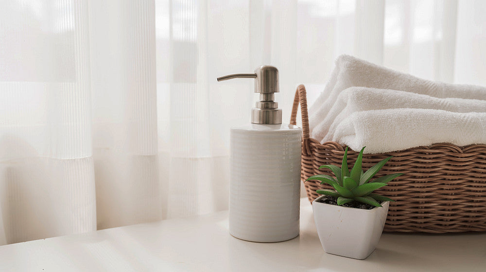Ceramic soap, shampoo bottles and white cotton towels in basket