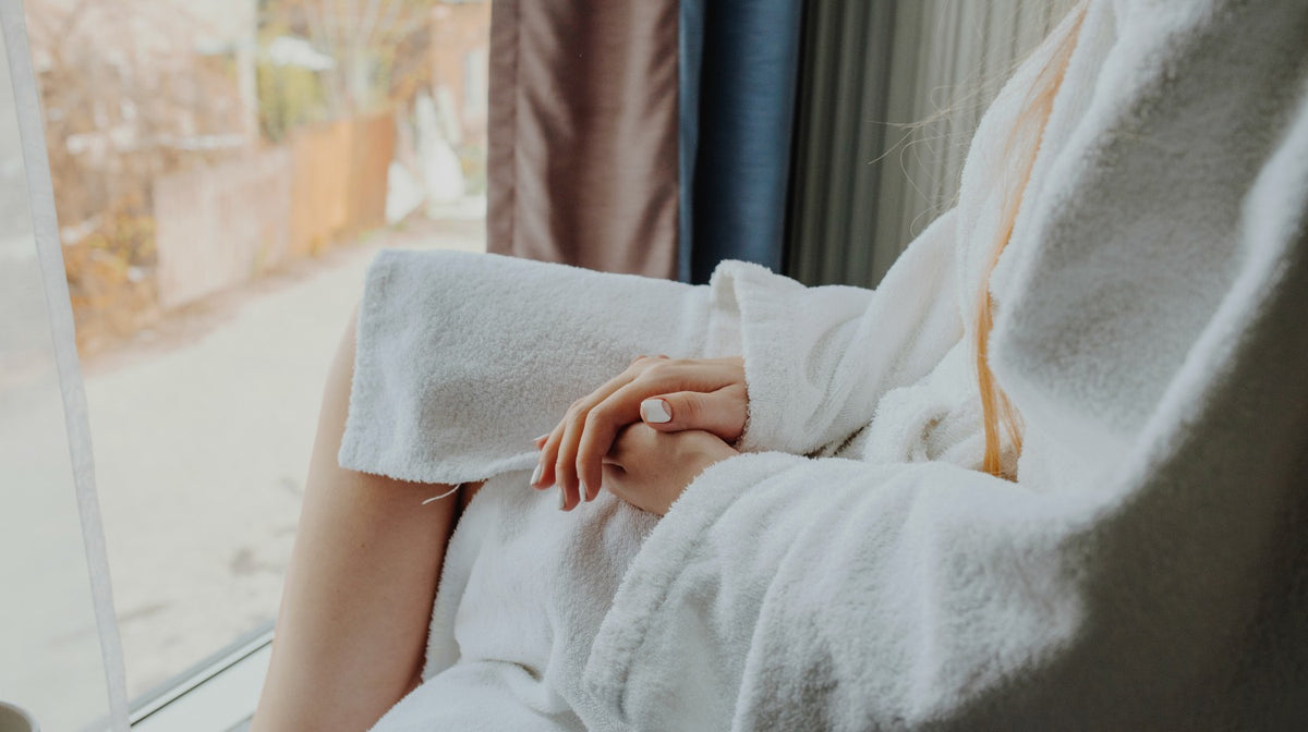 woman wearing bathrobe beside the window