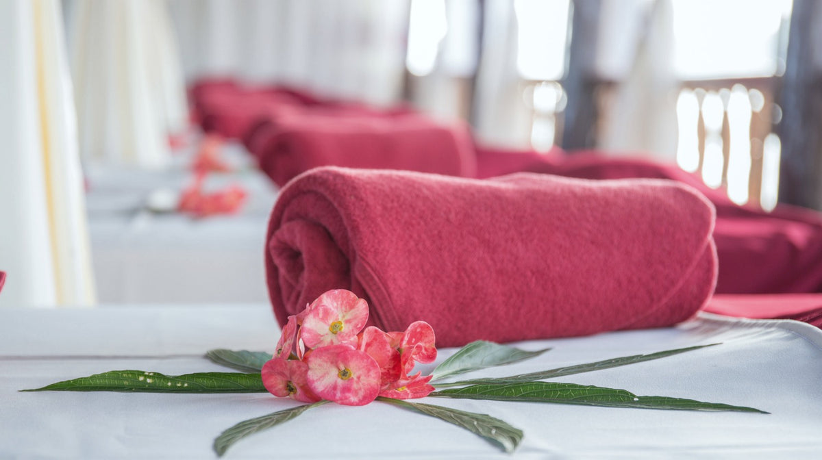 rolled pink bath towels on bench